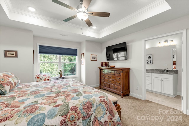 bedroom with ceiling fan, a raised ceiling, and ensuite bathroom