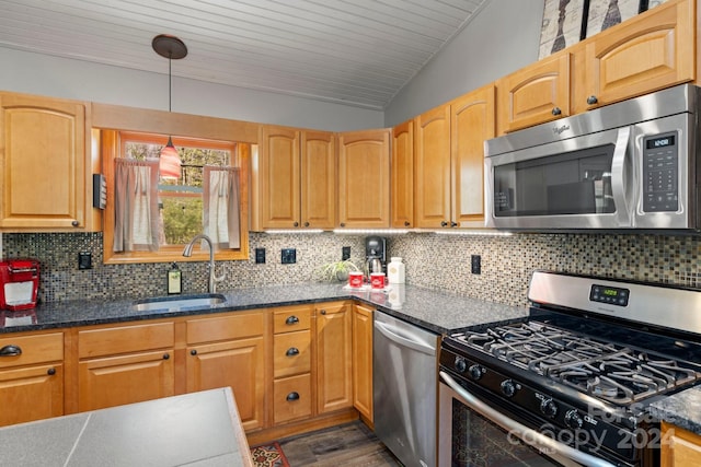 kitchen featuring lofted ceiling, sink, hanging light fixtures, stainless steel appliances, and decorative backsplash