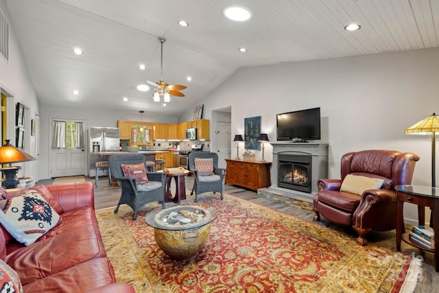 living room featuring vaulted ceiling, ceiling fan, and light hardwood / wood-style flooring