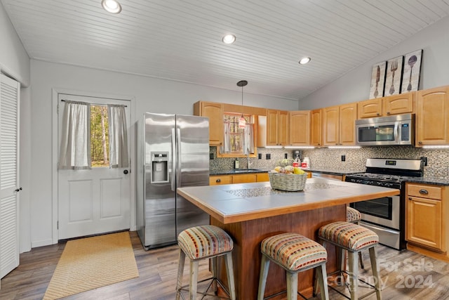 kitchen with appliances with stainless steel finishes, a center island, a breakfast bar area, and decorative light fixtures