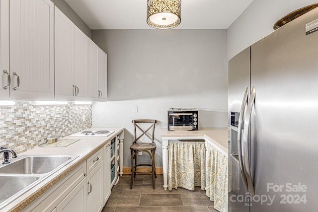 kitchen with white cabinetry, stainless steel fridge, sink, and tasteful backsplash