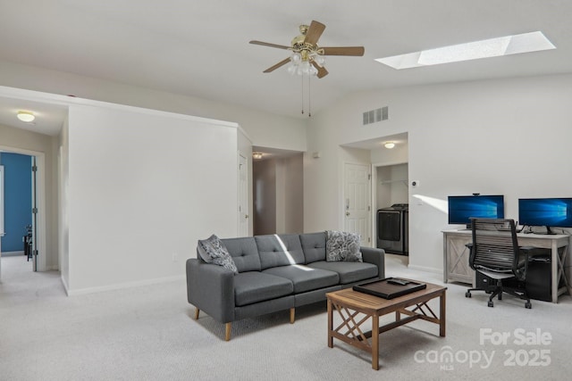 living room featuring washer / clothes dryer, light carpet, lofted ceiling with skylight, and ceiling fan