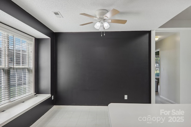 empty room featuring a textured ceiling, ceiling fan, and plenty of natural light