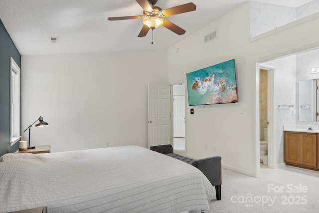 bedroom with sink, ensuite bathroom, light carpet, and ceiling fan