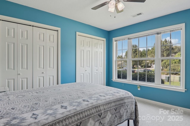 bedroom featuring multiple closets, ceiling fan, and carpet