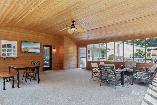 carpeted dining area featuring lofted ceiling, wood walls, ceiling fan, and wooden ceiling