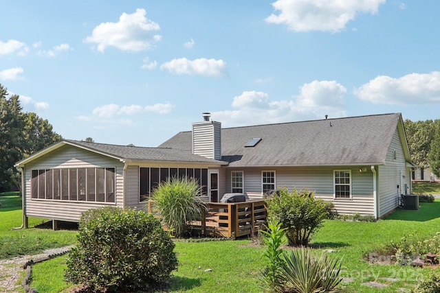 rear view of house featuring a deck, a yard, and a sunroom