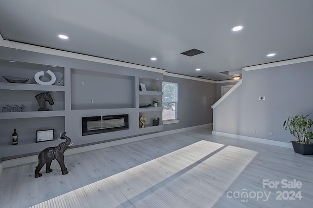 living area featuring recessed lighting, light wood-style flooring, built in shelves, and a glass covered fireplace