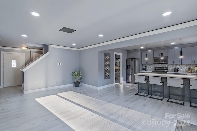 kitchen featuring gray cabinetry, stainless steel appliances, a kitchen breakfast bar, hanging light fixtures, and light countertops