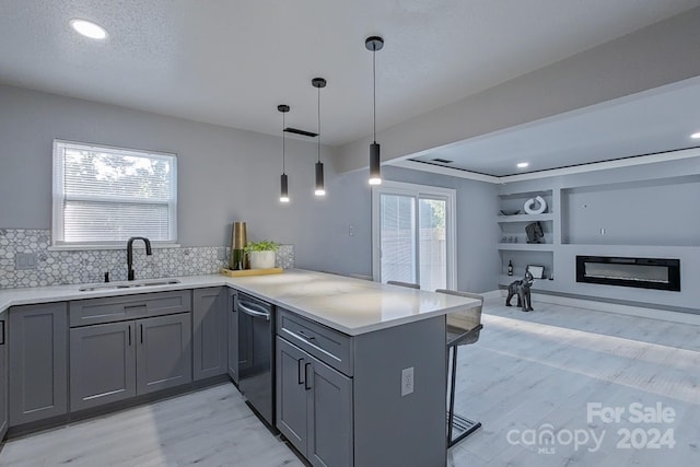 kitchen with a peninsula, a sink, open floor plan, hanging light fixtures, and light countertops