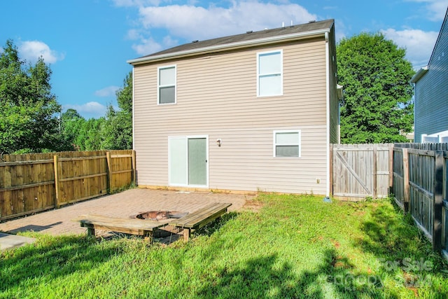 back of house with a yard, a fenced backyard, and a gate