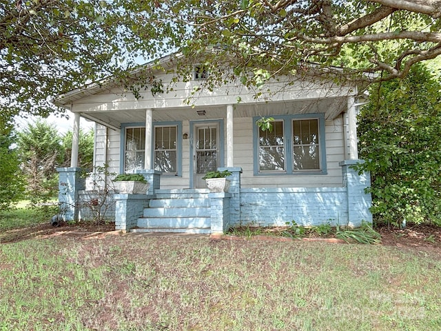 bungalow-style home with covered porch and a front yard