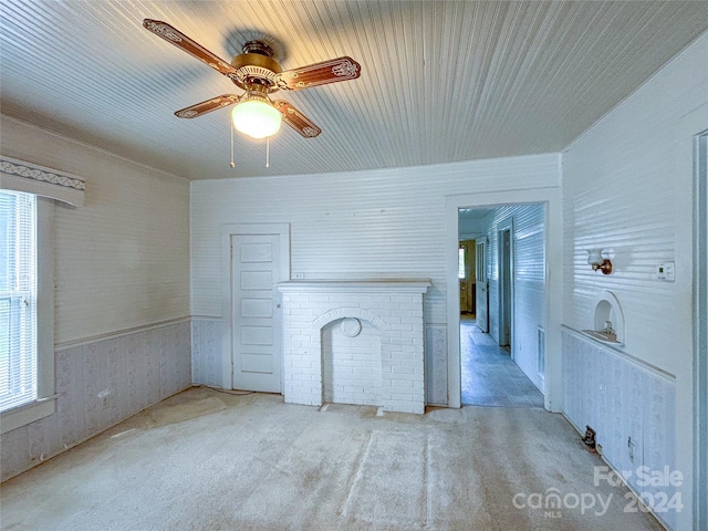 unfurnished living room with a fireplace, ceiling fan, and light colored carpet