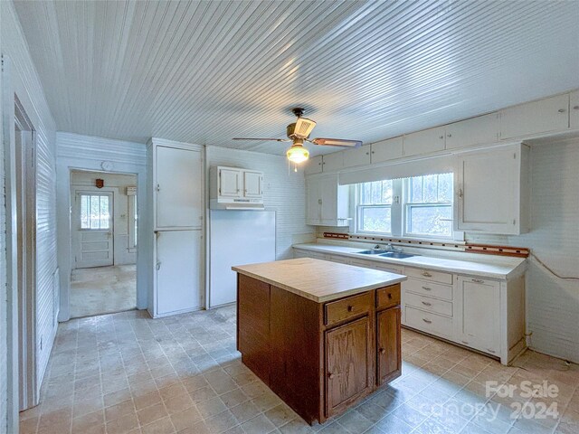 kitchen featuring white cabinetry, sink, light tile patterned floors, a kitchen island, and ceiling fan