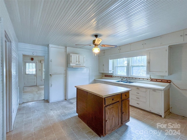 kitchen with white cabinetry, a kitchen island, sink, and ceiling fan