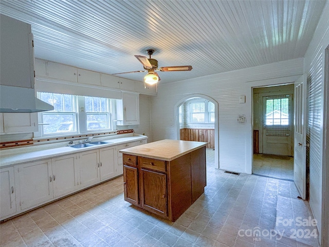 kitchen with white cabinetry, a center island, sink, exhaust hood, and ceiling fan