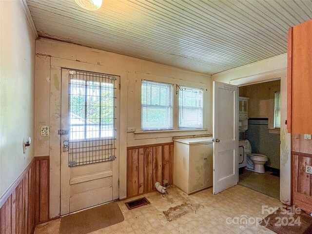 entryway featuring wood walls, light tile patterned floors, and wood ceiling