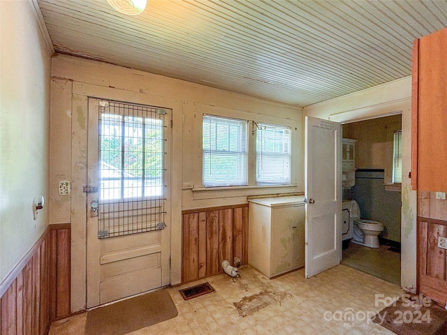 doorway to outside featuring wood ceiling and wooden walls