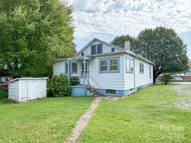 bungalow with a storage shed and a front lawn