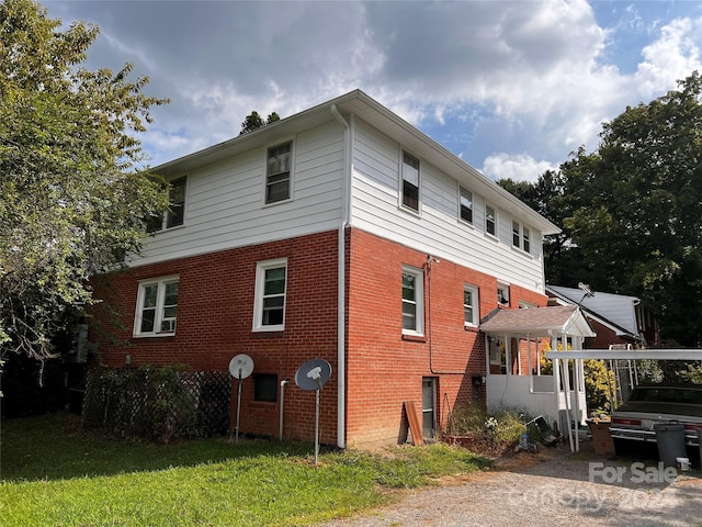 view of property exterior featuring brick siding and a yard