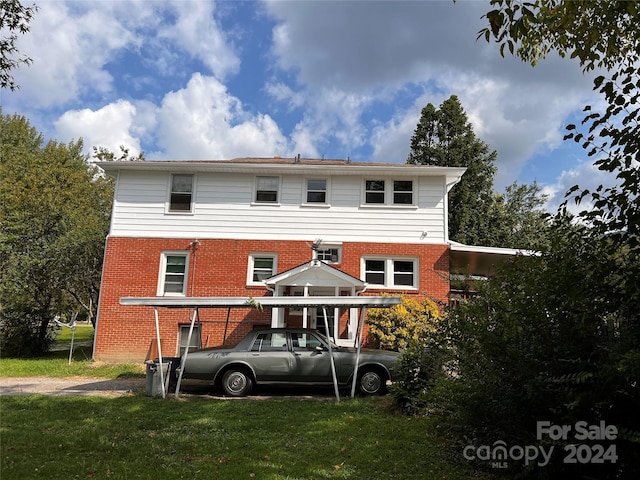 rear view of house featuring a carport, a yard, and brick siding