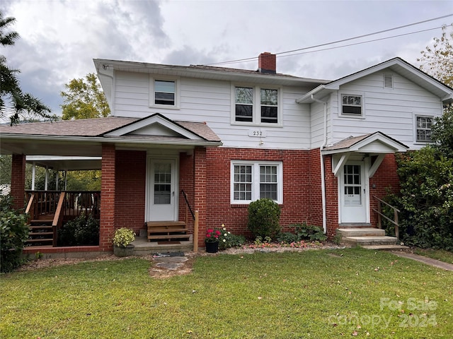 traditional-style home with entry steps, a shingled roof, a chimney, a front yard, and brick siding