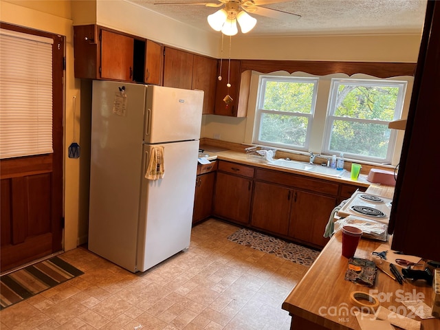 kitchen with a textured ceiling, light countertops, a sink, and freestanding refrigerator