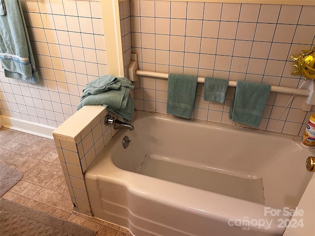 bathroom with a tub to relax in and tile patterned floors