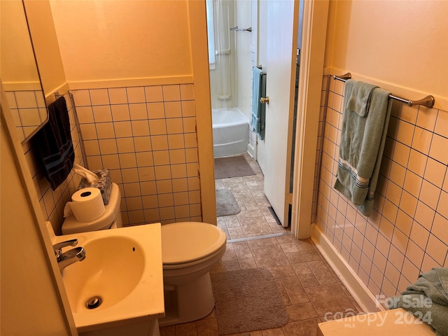 full bathroom with toilet, shower / bath combination, a sink, tile walls, and stone tile flooring