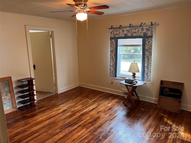 empty room featuring ceiling fan, visible vents, baseboards, and dark wood-type flooring