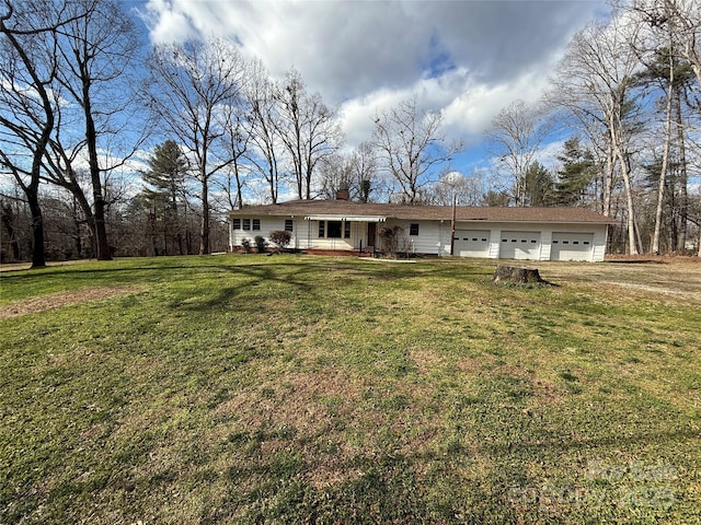 view of front of home featuring covered porch, a garage, and a front lawn