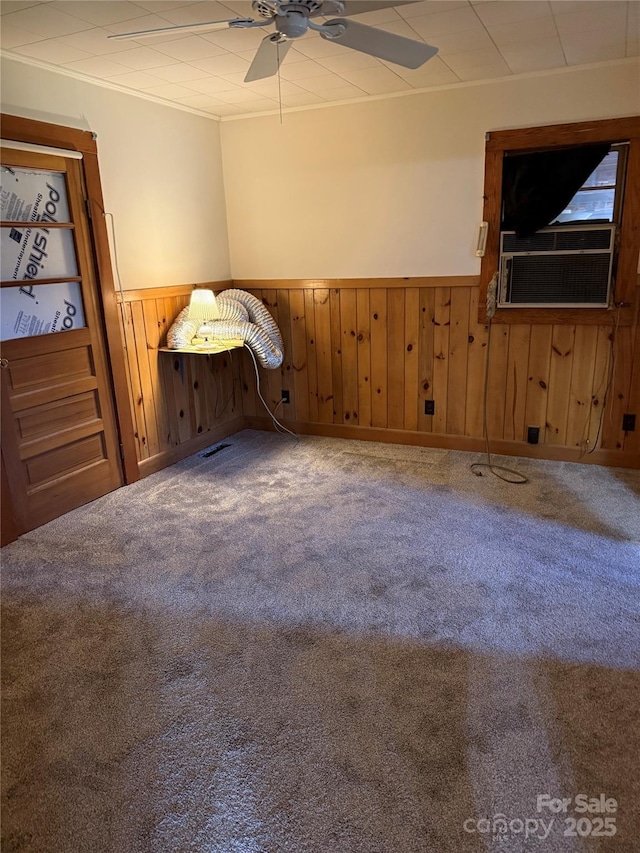 spare room with carpet flooring, ceiling fan, wood walls, and cooling unit