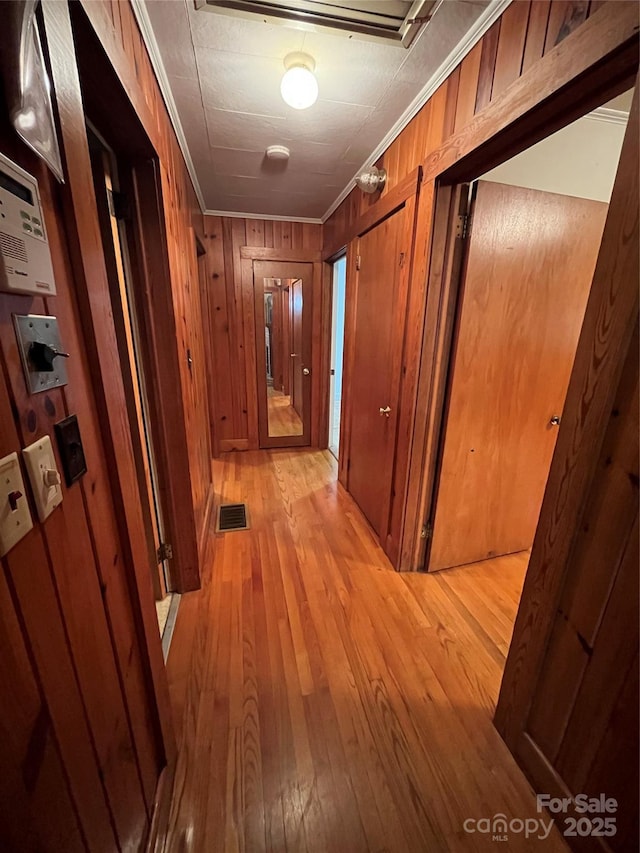 hall featuring ornamental molding and light hardwood / wood-style flooring