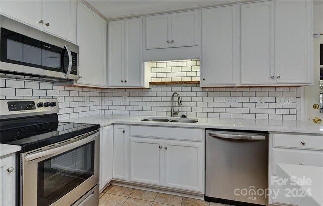 kitchen featuring appliances with stainless steel finishes, light tile patterned floors, sink, and white cabinets