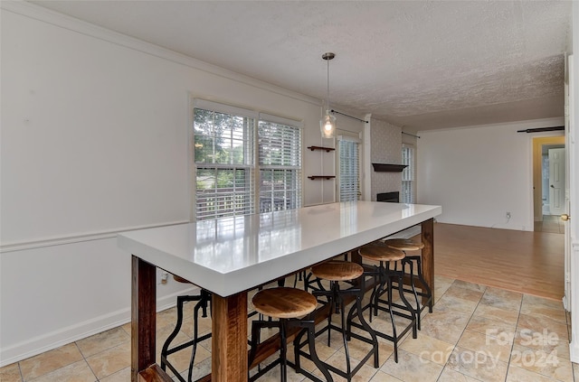 dining room with a textured ceiling, ornamental molding, and light wood-type flooring