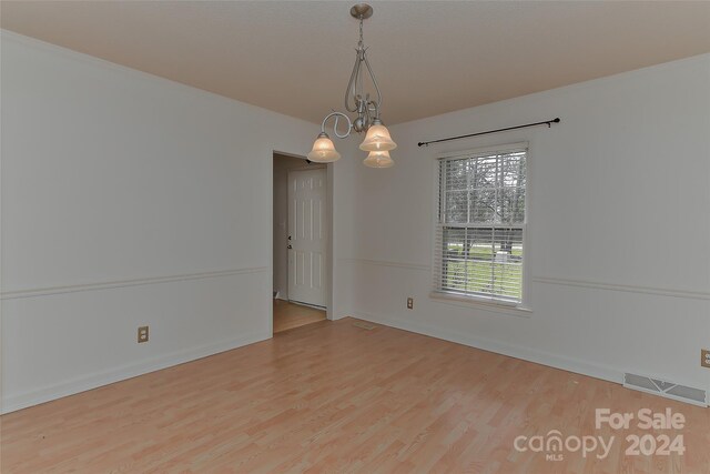 spare room featuring light hardwood / wood-style flooring and a chandelier