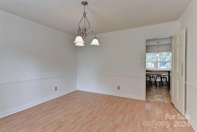 spare room with a chandelier and light hardwood / wood-style flooring