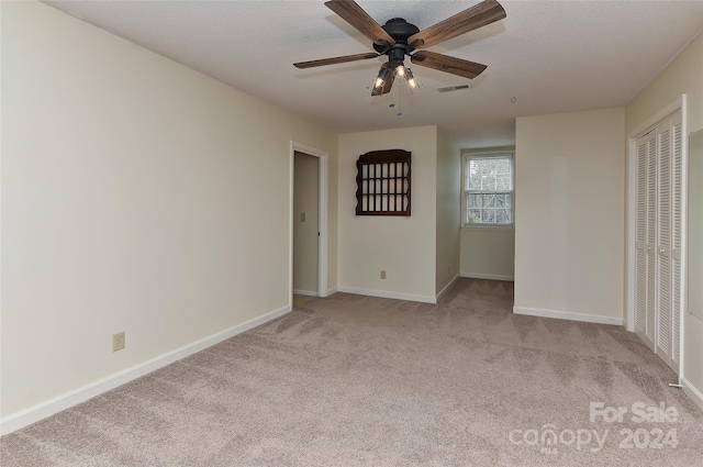 carpeted empty room featuring ceiling fan and a textured ceiling