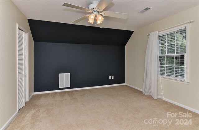 additional living space featuring a healthy amount of sunlight, ceiling fan, light colored carpet, and vaulted ceiling