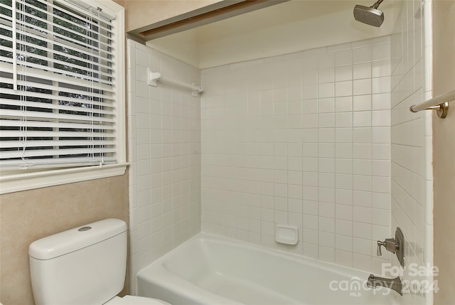 bathroom featuring tiled shower / bath combo and toilet