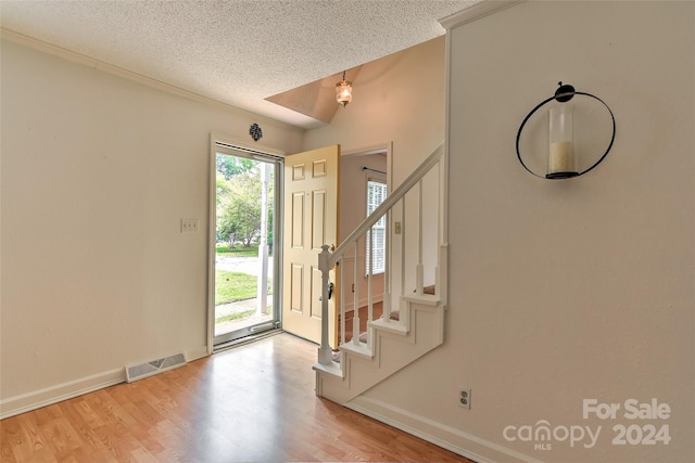 foyer with a textured ceiling, a healthy amount of sunlight, and hardwood / wood-style floors