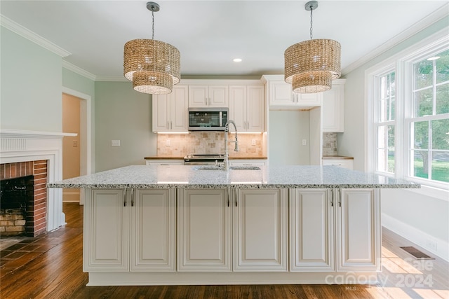 kitchen featuring a wealth of natural light, dark wood-type flooring, light stone counters, and a fireplace