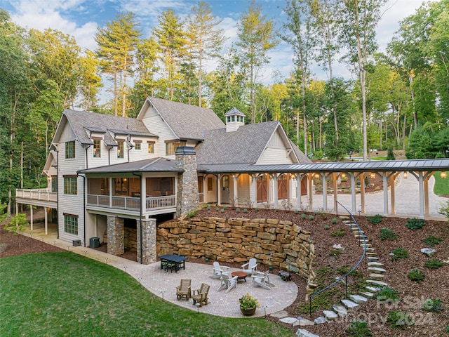 rear view of property featuring a lawn, a patio, and a fire pit