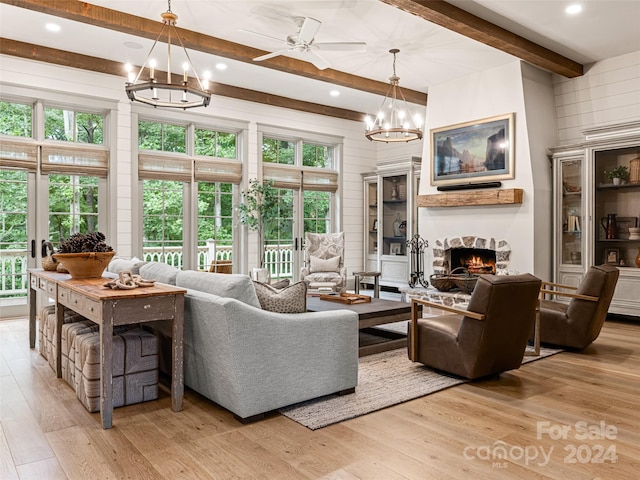 living room featuring beam ceiling, ceiling fan with notable chandelier, light hardwood / wood-style floors, and wood walls