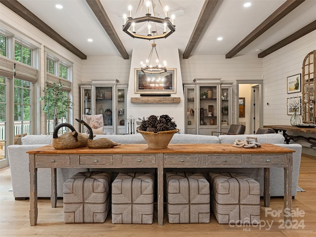 living room with light hardwood / wood-style floors, an inviting chandelier, and beamed ceiling