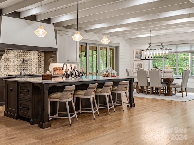 kitchen with white cabinetry, a breakfast bar, custom exhaust hood, and light wood-type flooring