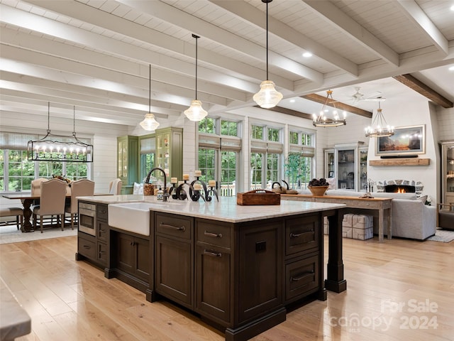 kitchen with pendant lighting, a healthy amount of sunlight, dark brown cabinetry, and a chandelier