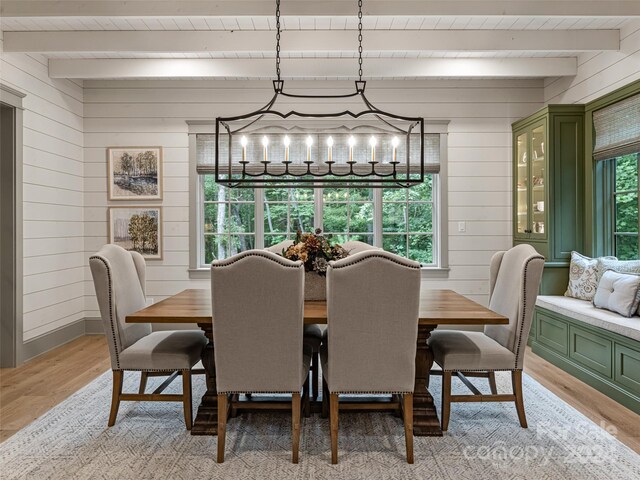 dining space featuring light hardwood / wood-style floors, beam ceiling, and a chandelier