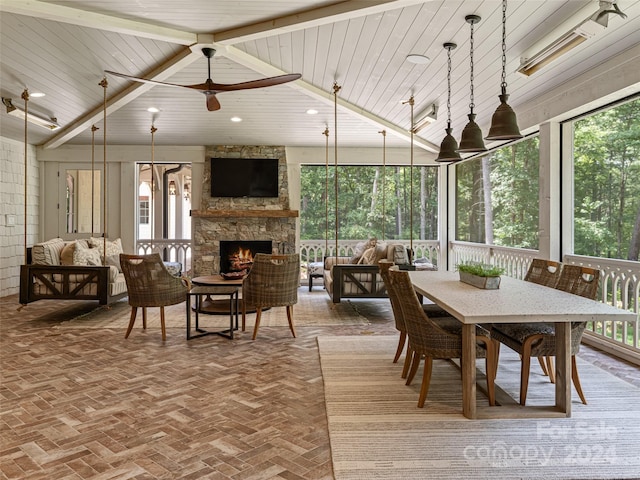 sunroom with ceiling fan, a fireplace, wooden ceiling, and lofted ceiling with beams