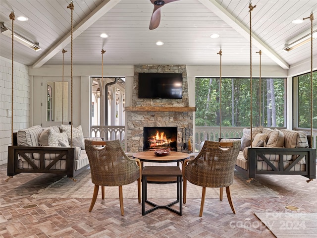 living room with a stone fireplace, a healthy amount of sunlight, and beam ceiling